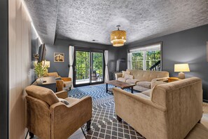 A modern living room with a sofa, armchairs, a coffee table, and a fireplace.