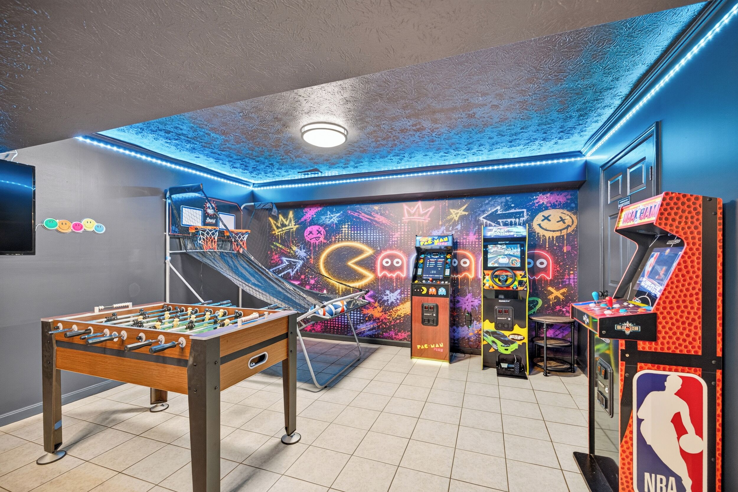 Une pièce équipée d’un baby-foot, d’un jeu d’arcade de basket-ball et d’une table de billard.
