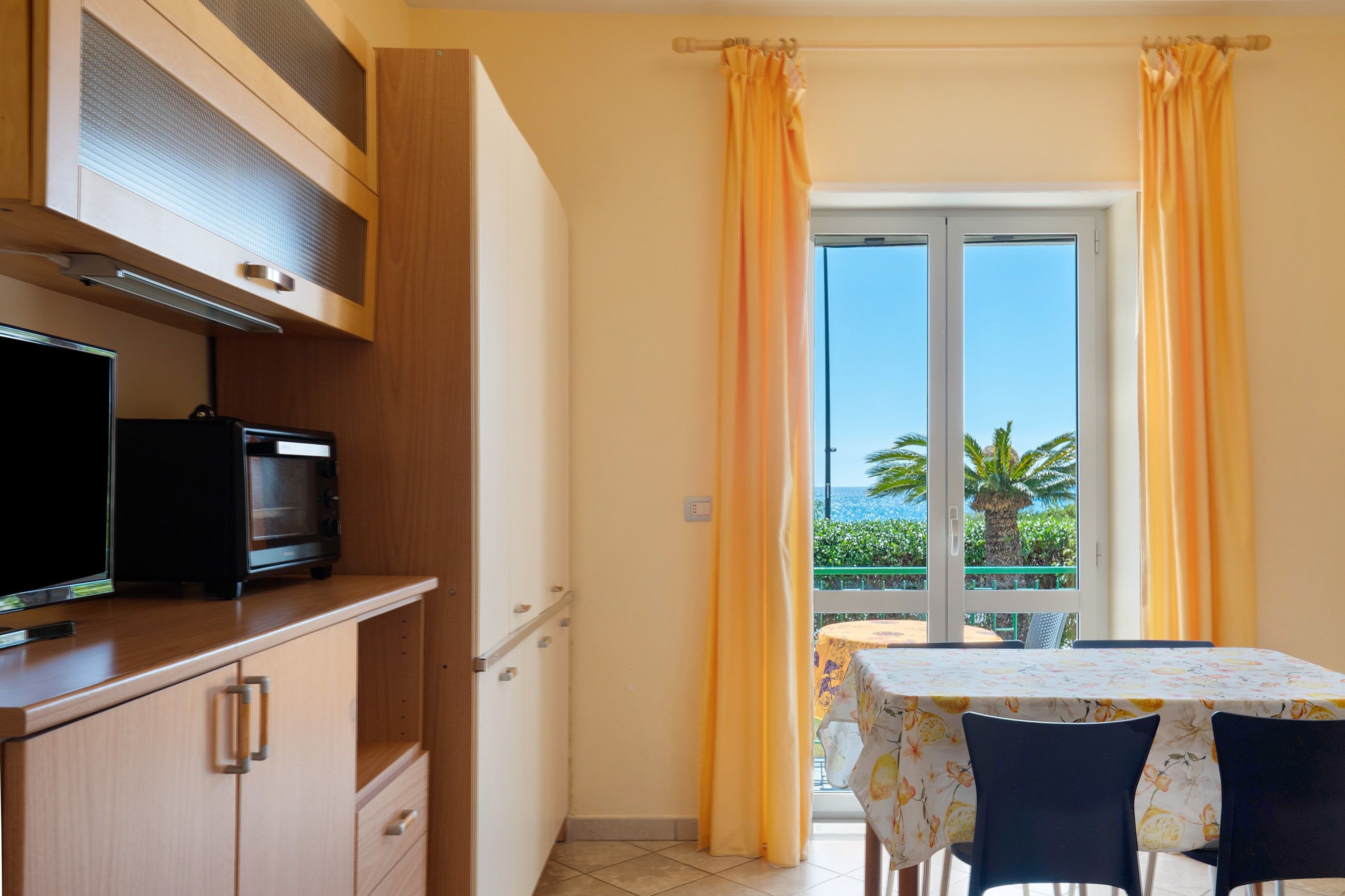 A compact kitchen with a microwave, a small refrigerator, and a wooden cabinet.