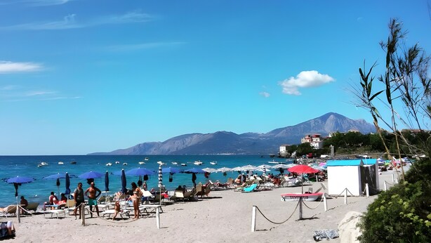 A beach with sun loungers and umbrellas, a boat, and mountains in the background. - Apartment 'Comics' with sea view, Wi-Fi and air conditioning (Villammare)