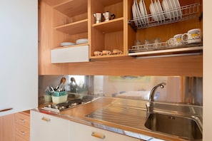 Una cocina con armarios de madera, un lavamanos de acero inoxidable y un escurreplatos.