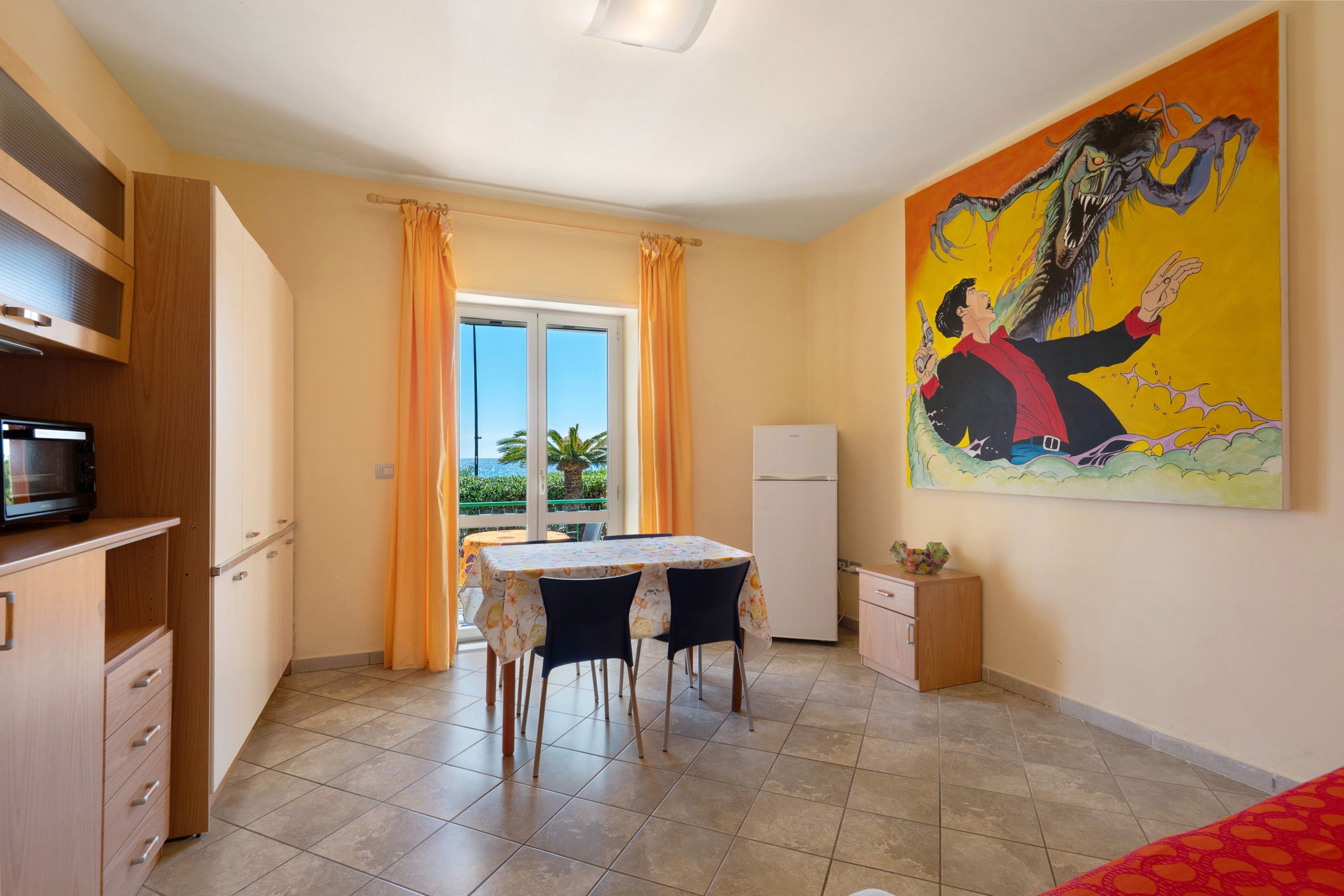 A compact kitchen with a dining area, a refrigerator, and a microwave.