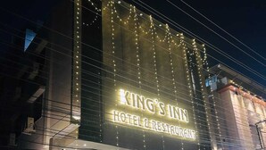 Un edificio con un cartel iluminado grande que dice 'KING'S INN HOTEL & RESTAURANT'.