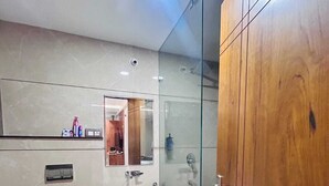 Un baño moderno con inodoro, lavamanos y ducha con mampara de vidrio.