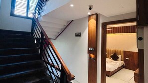 Una escalera conduce a un dormitorio con cama, ventana y puerta con un cartel.