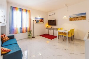 Una sala de estar moderna con un sofá azul, una zona de comedor con sillas amarillas, un tapete rojo y un cuadro en la pared.