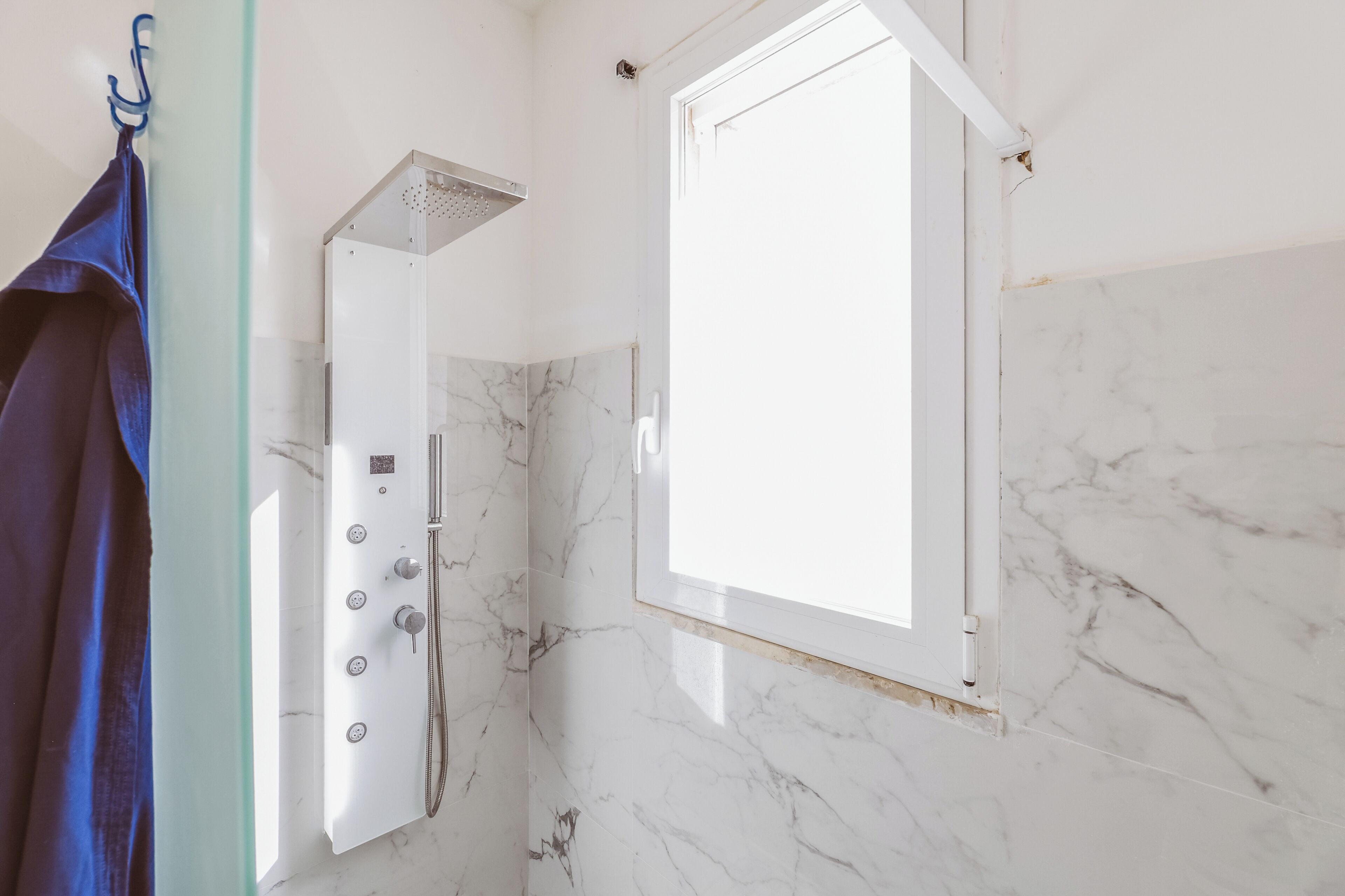 Une salle de bain avec une douche, un porte-serviettes et une fenêtre.