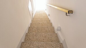 A staircase with a handrail on the right, leading to a bright area at the top.