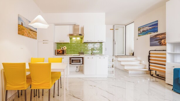 A modern kitchen with white cabinets, a green backsplash, and a built-in oven.
