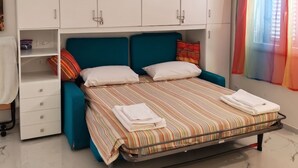A bedroom with a bed, a wardrobe, a desk, and a colorful window.