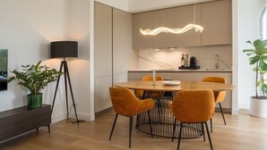 Un comedor moderno con una mesa redonda, cuatro sillas, una lámpara de pie y una cocina al fondo.