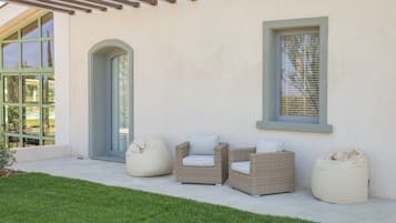 A patio with wicker furniture, a bean bag, and a glass door.