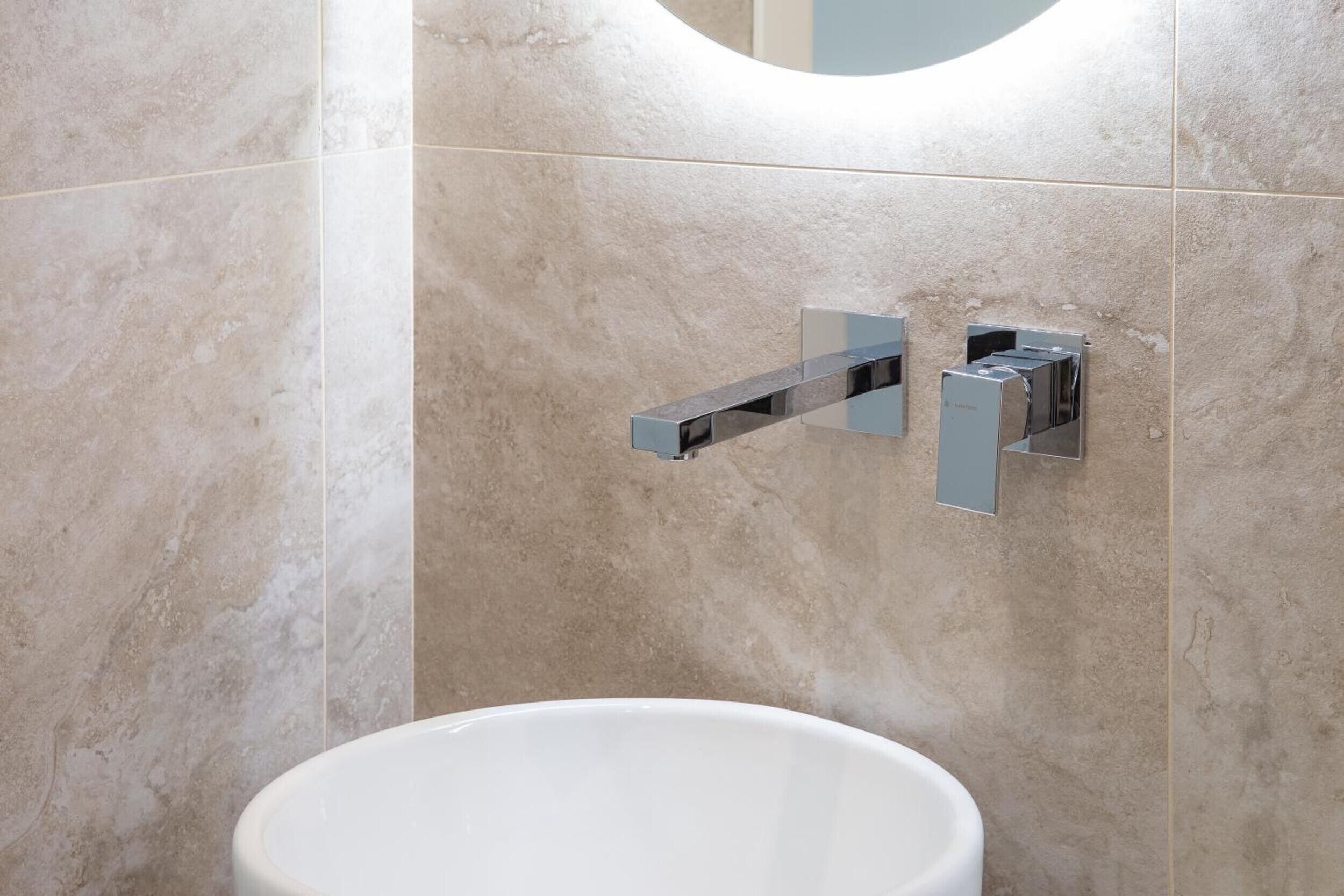 Une salle de bain avec un lavabo blanc, un miroir et des accessoires en chrome.
