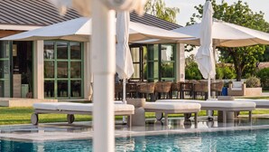 A swimming pool with lounge chairs and umbrellas, surrounded by a building with large windows and outdoor seating. - Pool View Suite 205, 50 m² with Bathtub, Breakfast Included (Fucecchio)