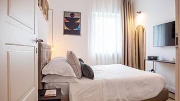 Une chambre à coucher bien rangée, avec un lit, des tables de chevet, un téléviseur et un tableau accroché au mur.