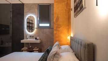 Ein modernes Schlafzimmer mit Bett, Nachttisch, Spiegel, Wandleuchte und einer Duschkabine.