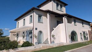 Una casa grande de dos pisos con una entrada destacada, varias ventanas y un porche cubierto.