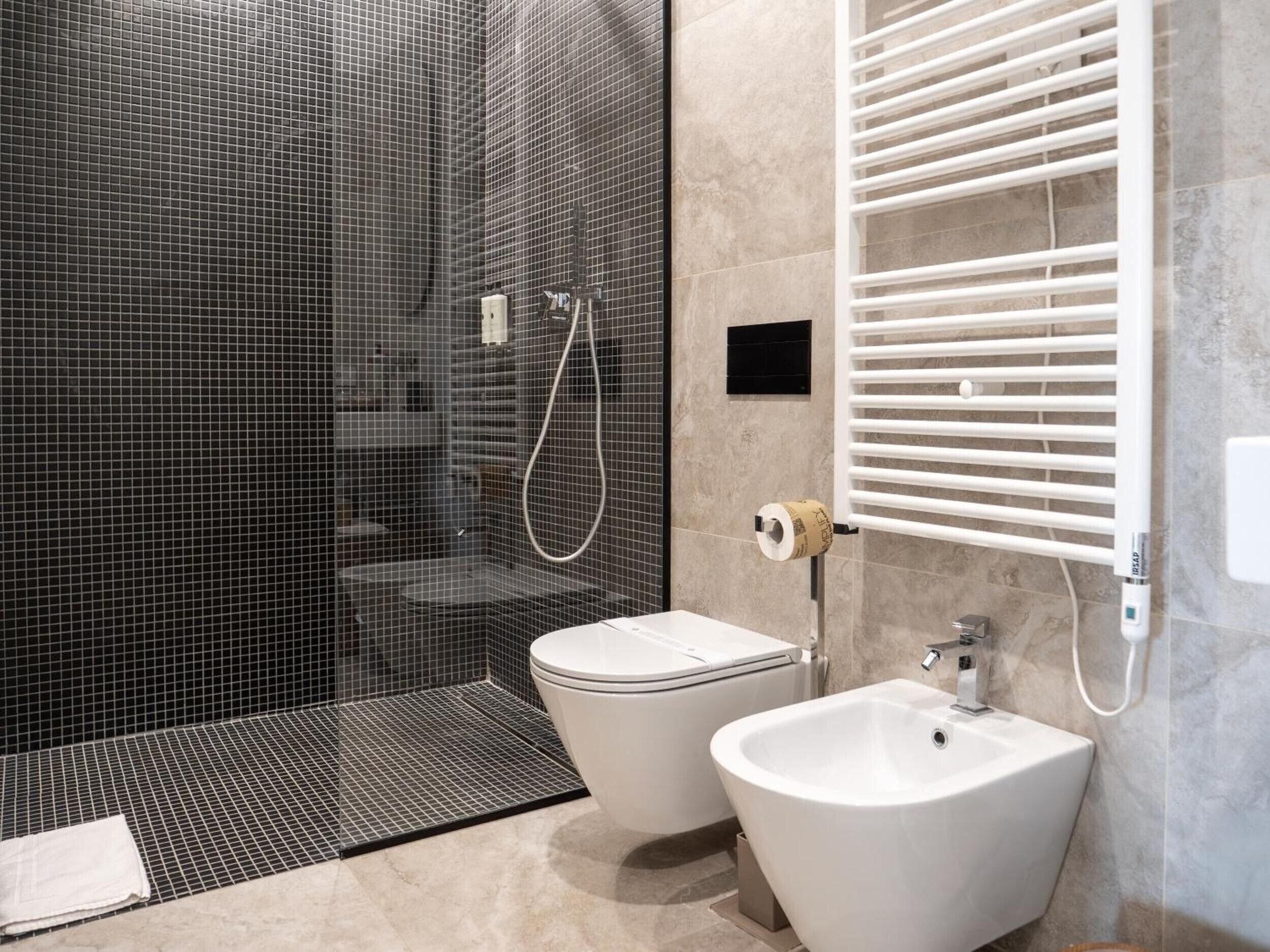 A modern bathroom with a glass-enclosed shower, a white toilet, and a bidet.