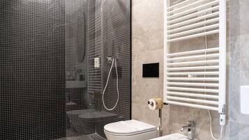 A modern bathroom with a glass-enclosed shower, a white toilet, and a bidet.