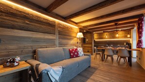 Indbydende interiør med trævæg, sofa, spiseplads og køkken.