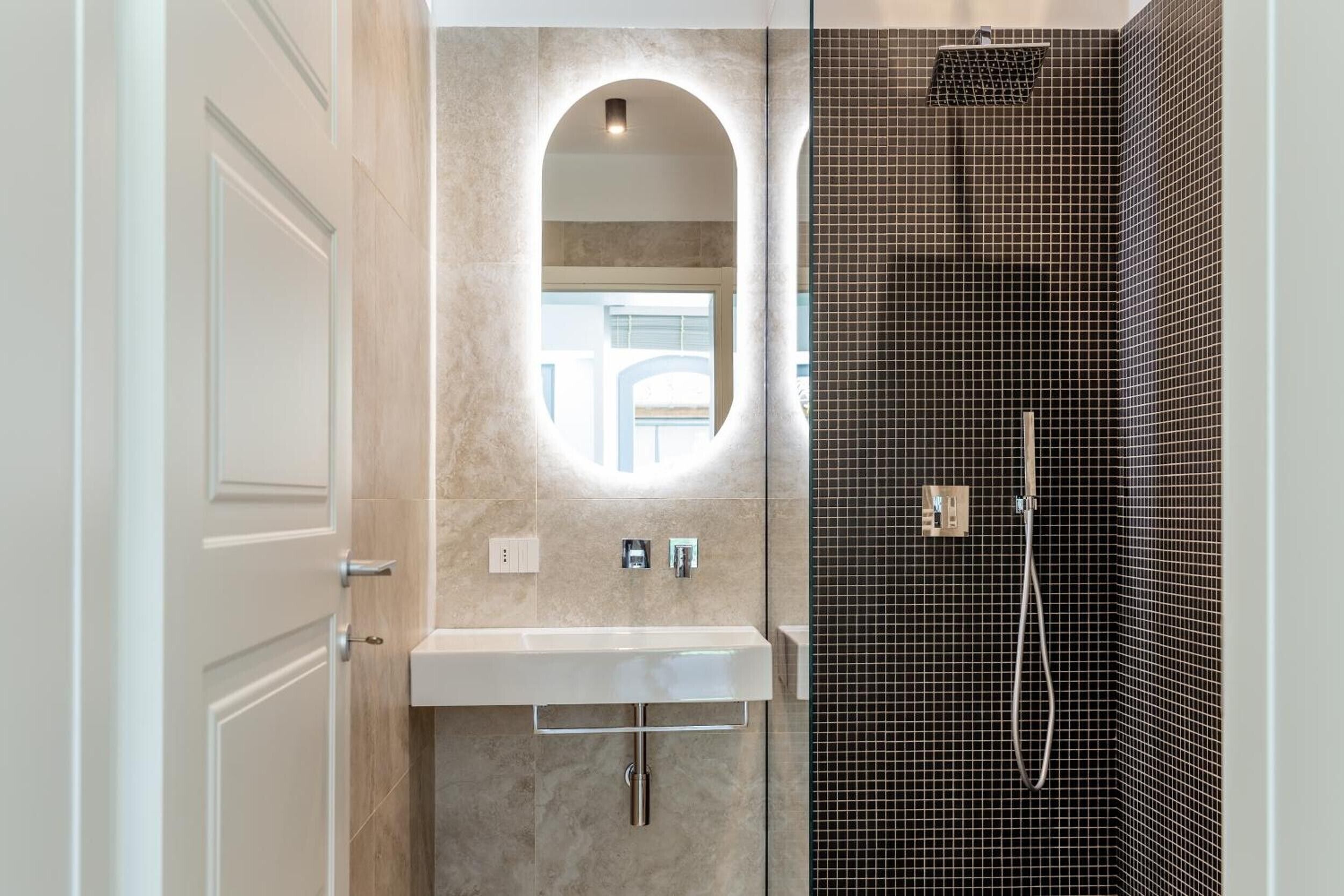 Un bagno con specchio, lavandino e doccia.