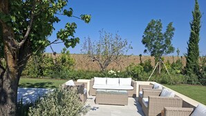 Eine Terrasse im Freien mit Korbmöbeln und einem gepflasterten Weg.