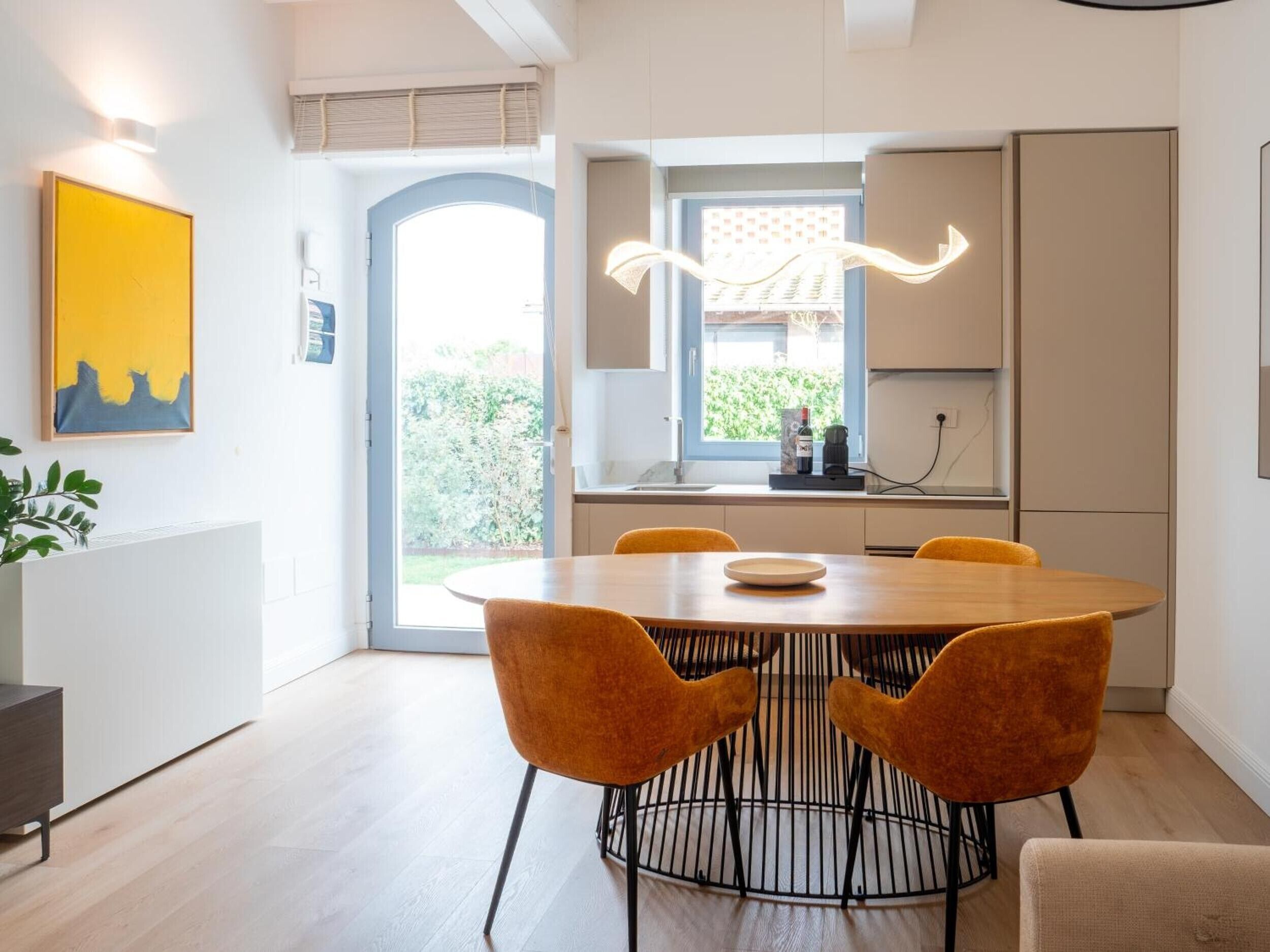 Un'area pranzo moderna con un tavolo rotondo, quattro sedie e vista sull'esterno.