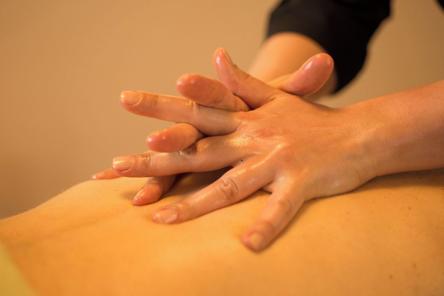 A close-up of hands performing a massage on a person's back.