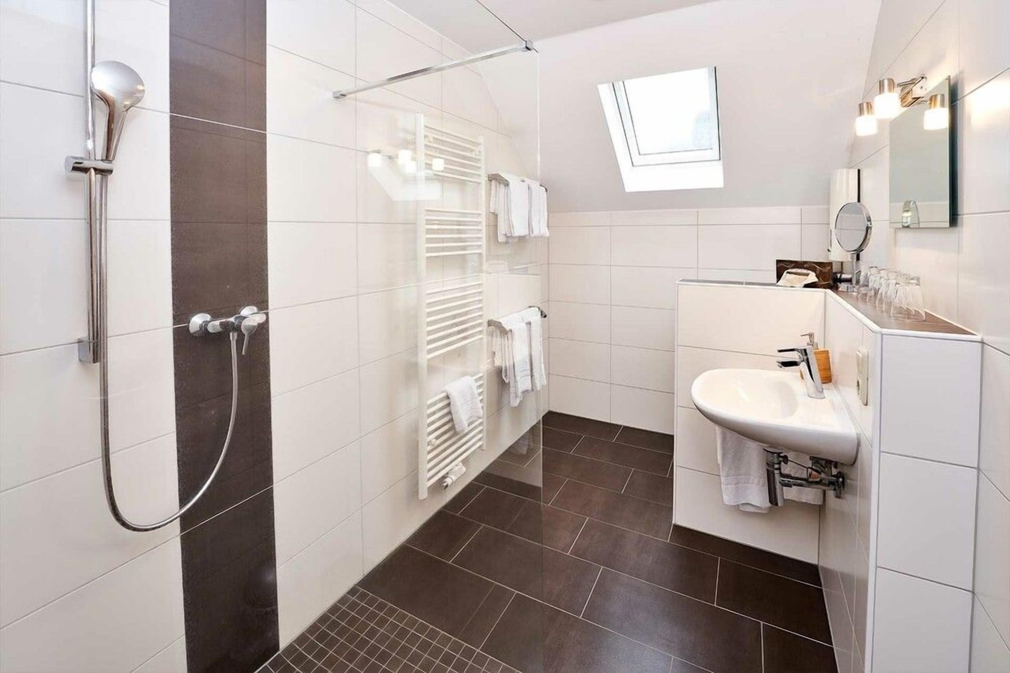 Un baño moderno con ducha, lavamanos y toallero.