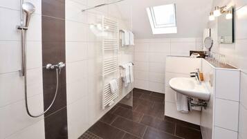 Un baño moderno con ducha, lavamanos y toallero.
