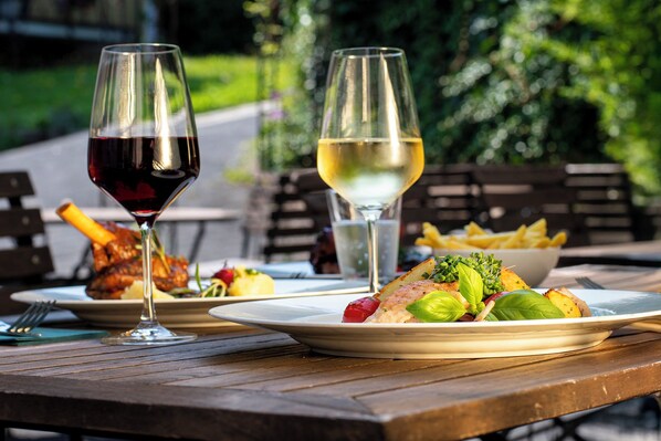 Une table à manger avec des assiettes remplies de nourriture, deux verres à vin et une fourchette.