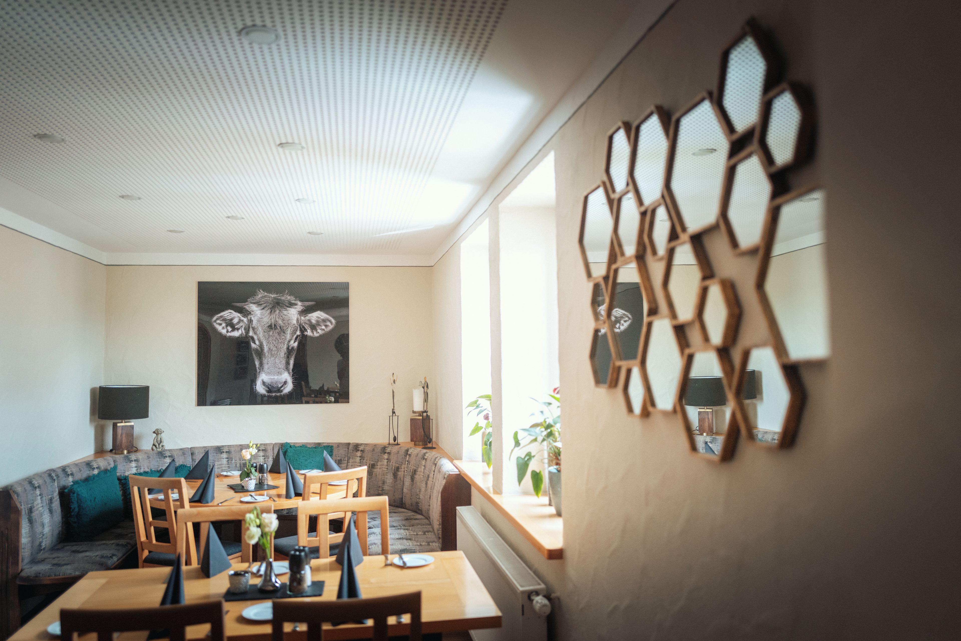 Un coin repas avec une table dressée pour quatre personnes, un canapé et un miroir fixé au mur.