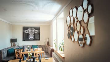 Un coin repas avec une table dressée pour quatre personnes, un canapé et un miroir fixé au mur.
