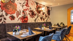 En restaurant med båse, borde og blomsterudsmykket vægkunst.