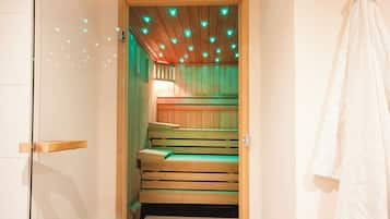 Een sauna met houten banken en een betegelde vloer, een handdoek hangt aan de muur en een deur met houten frame.