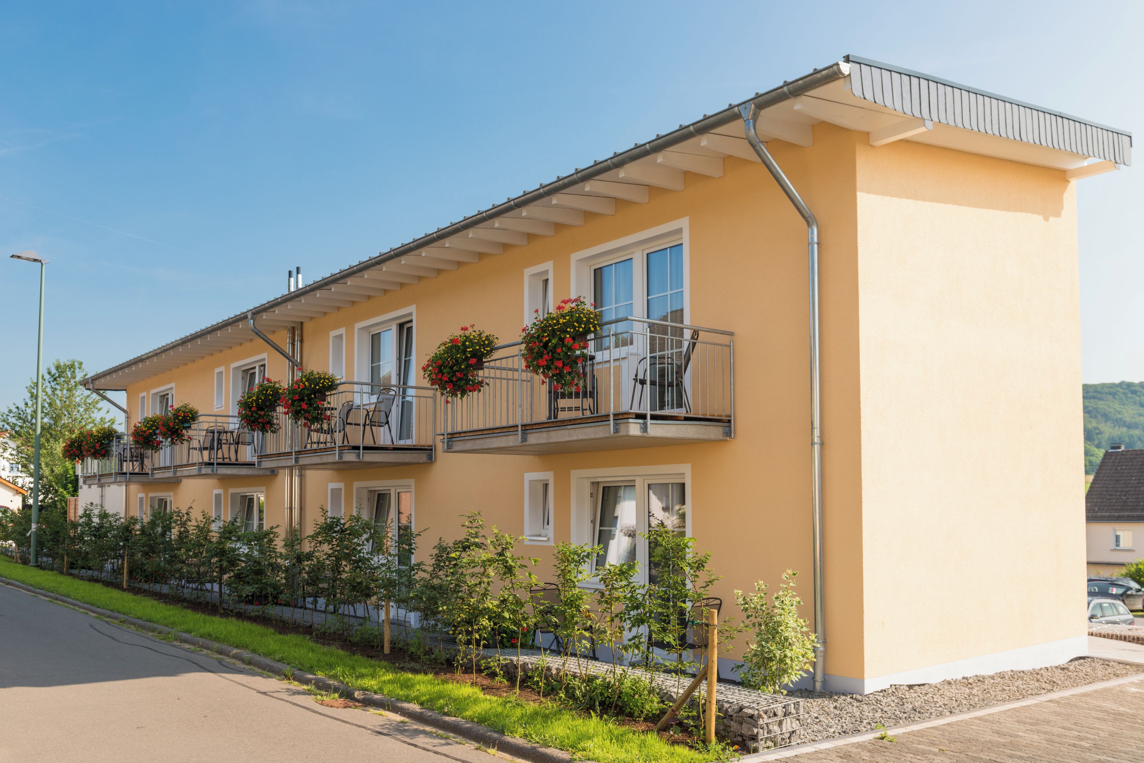 Un immeuble à deux étages doté de balcons, une allée pavée et un ciel dégagé.