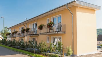 Un immeuble à deux étages doté de balcons, une allée pavée et un ciel dégagé.