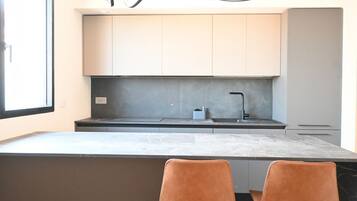 A modern kitchen with a marble countertop, two brown chairs, and a grey backsplash.