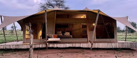 Una tienda safari con terraza de madera, un sofá y una zona de comedor.