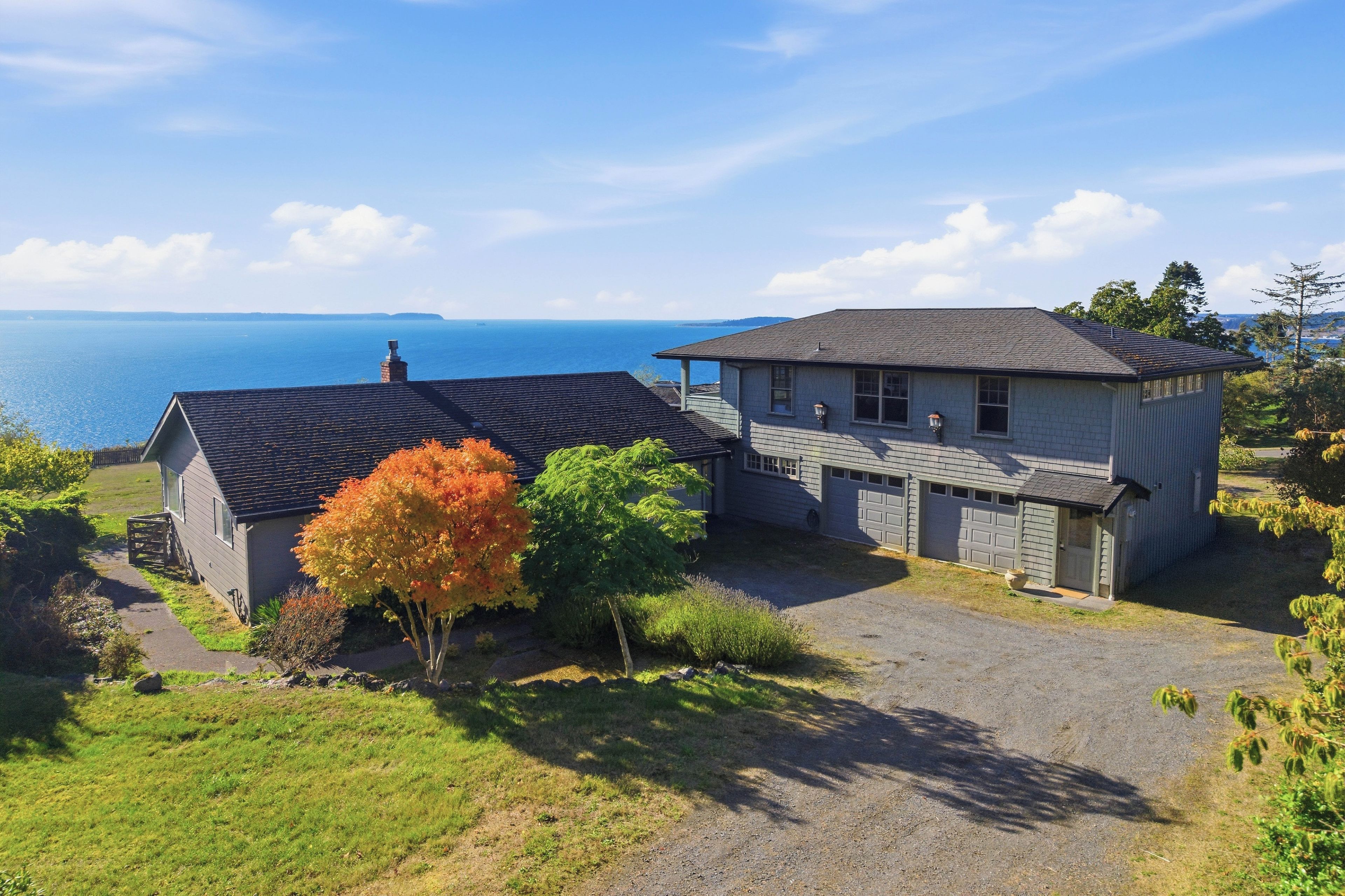 A two-story house with a garage, a driveway, and a view of the sea.