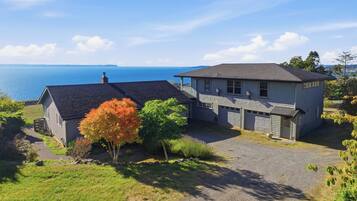 A two-story house with a garage, a driveway, and a view of the sea.