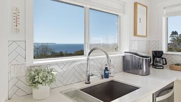 A modern kitchen with a large window, a stainless steel sink, and a coffee maker.