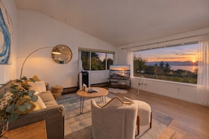 Een moderne woonkamer met een groot raam, een flatscreen televisie en een gezellige zithoek.