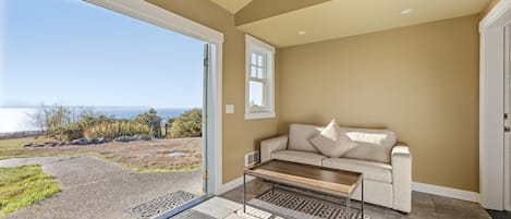 Una habitación con vista al océano, un sofá, una mesa de centro y una puerta.
