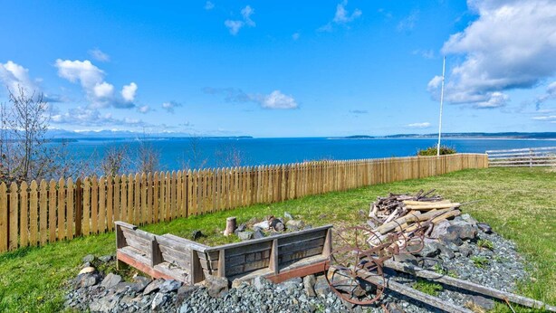 A coastal view with a wooden fence, a bench, and a rusty bicycle wheel. - Perch - 2BR Waterfront Bluff | Sunset Views | Free Parking (Coupeville)
