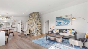Un espacio habitable moderno con chimenea de piedra, una zona de comedor y una sala de estar con alfombra azul.