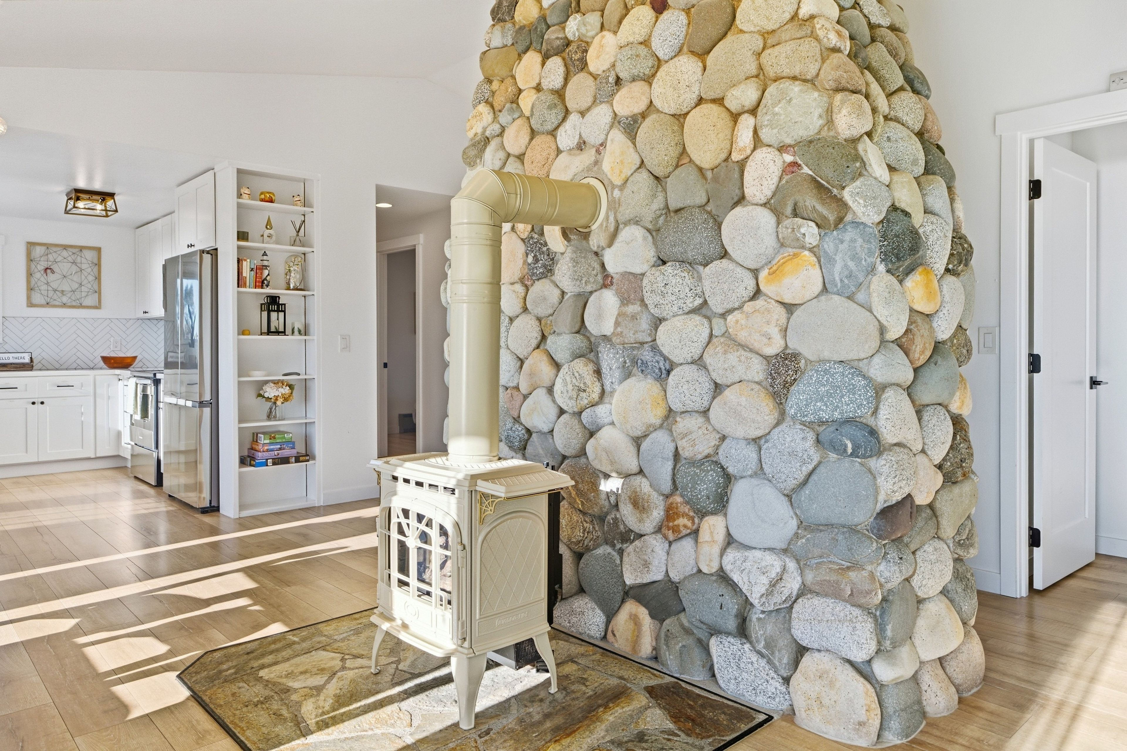 Una cocina moderna con armarios blancos, estufa integrada y un muro decorativo de piedra.