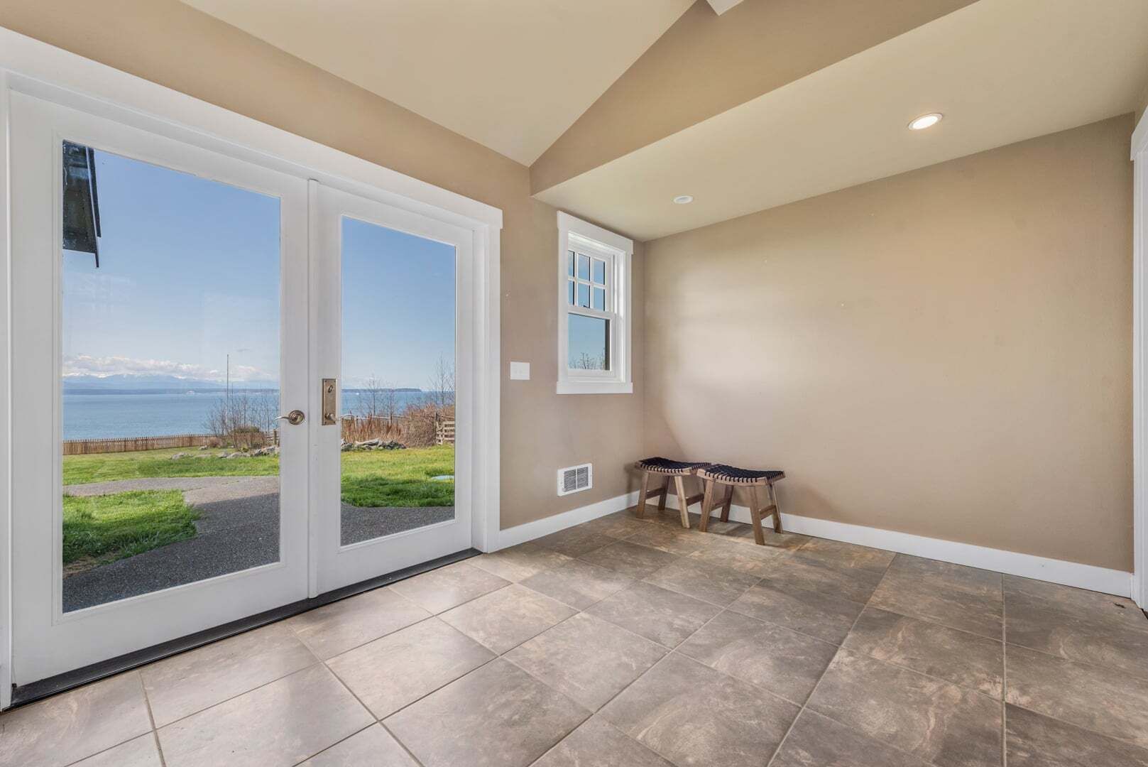 A room with a view of the sea, a bench, and a door leading outside.