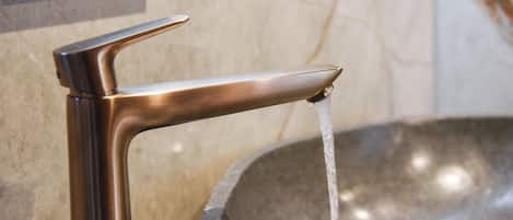 Un lavamanos moderno con grifo de un solo mando y un lavabo de piedra.