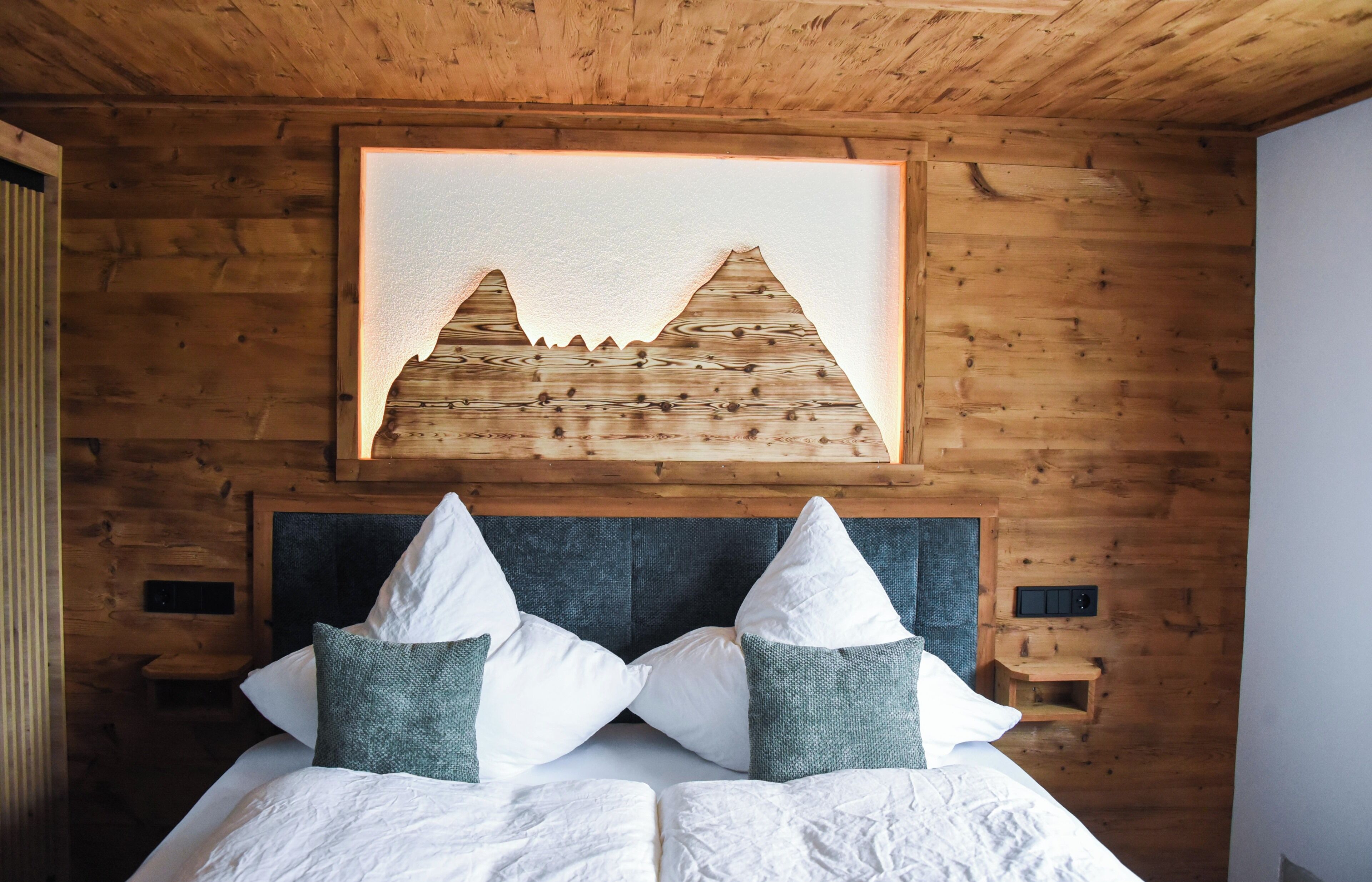 A wooden cabin-style bedroom with a bed, pillows, and a framed picture on the wall.